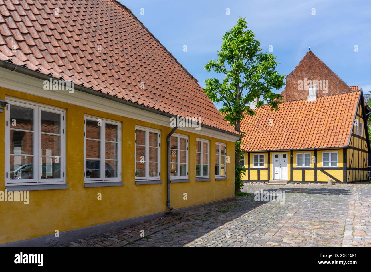 Svendborg, Danimarca - 10 giugno 2021: Edifici gialli e calze a graticcio su una strada acciottolata nel centro storico di Svendborg Foto Stock