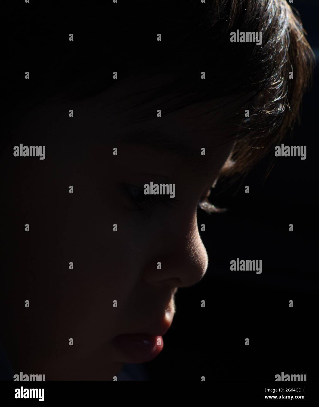 Silhouette di un ragazzo su sfondo nero. Primo piano Ritratto di un bambino. Profilo della faccia Foto Stock