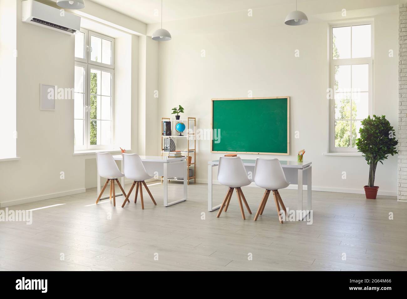 Moderno interno vuoto con scrivanie, sedie e lavagna. Camera scuola luminosa con arredamento confortevole e grandi finestre Foto Stock