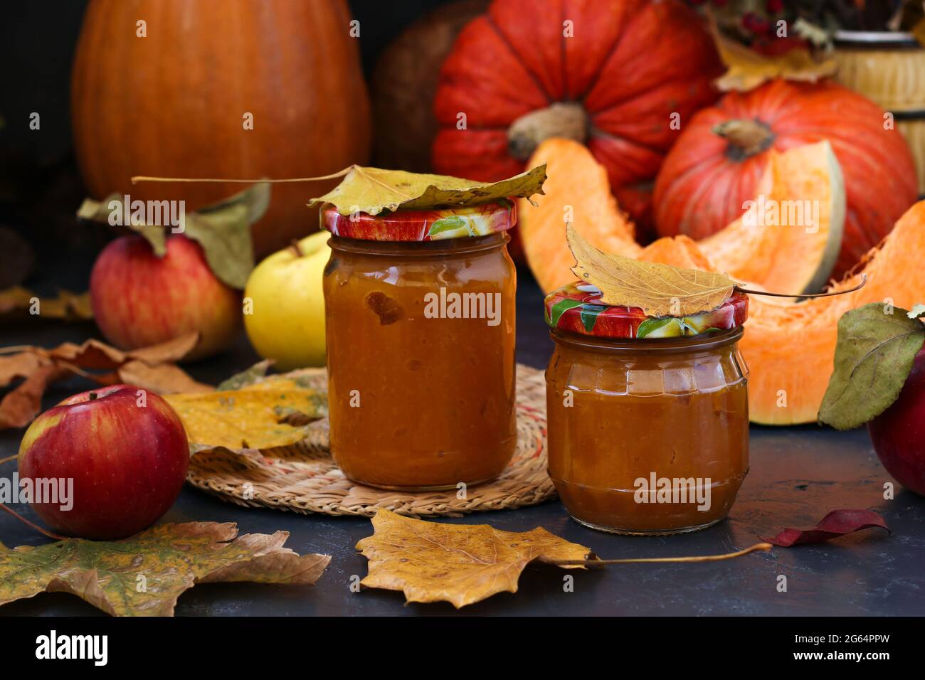 Zucca purea fatta in casa e mele per bambini in banche su uno sfondo scuro. Autunno ancora vita Foto Stock