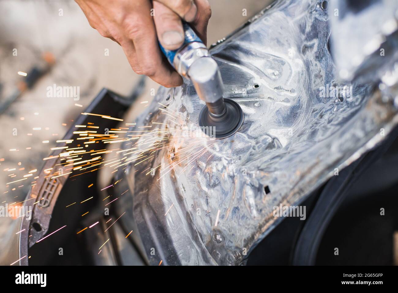 Lavorazione del metallo con un utensile di rettifica elettrico a una profondità di campo poco profonda. Le scintille volano nel processo Foto Stock
