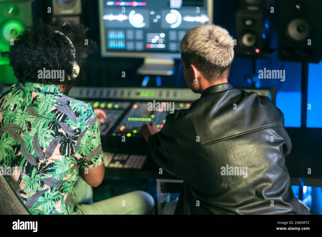 Giovani tecnici audio si divertono a lavorare con il suono del mixer pannello di controllo nello studio di registrazione musicale Foto Stock