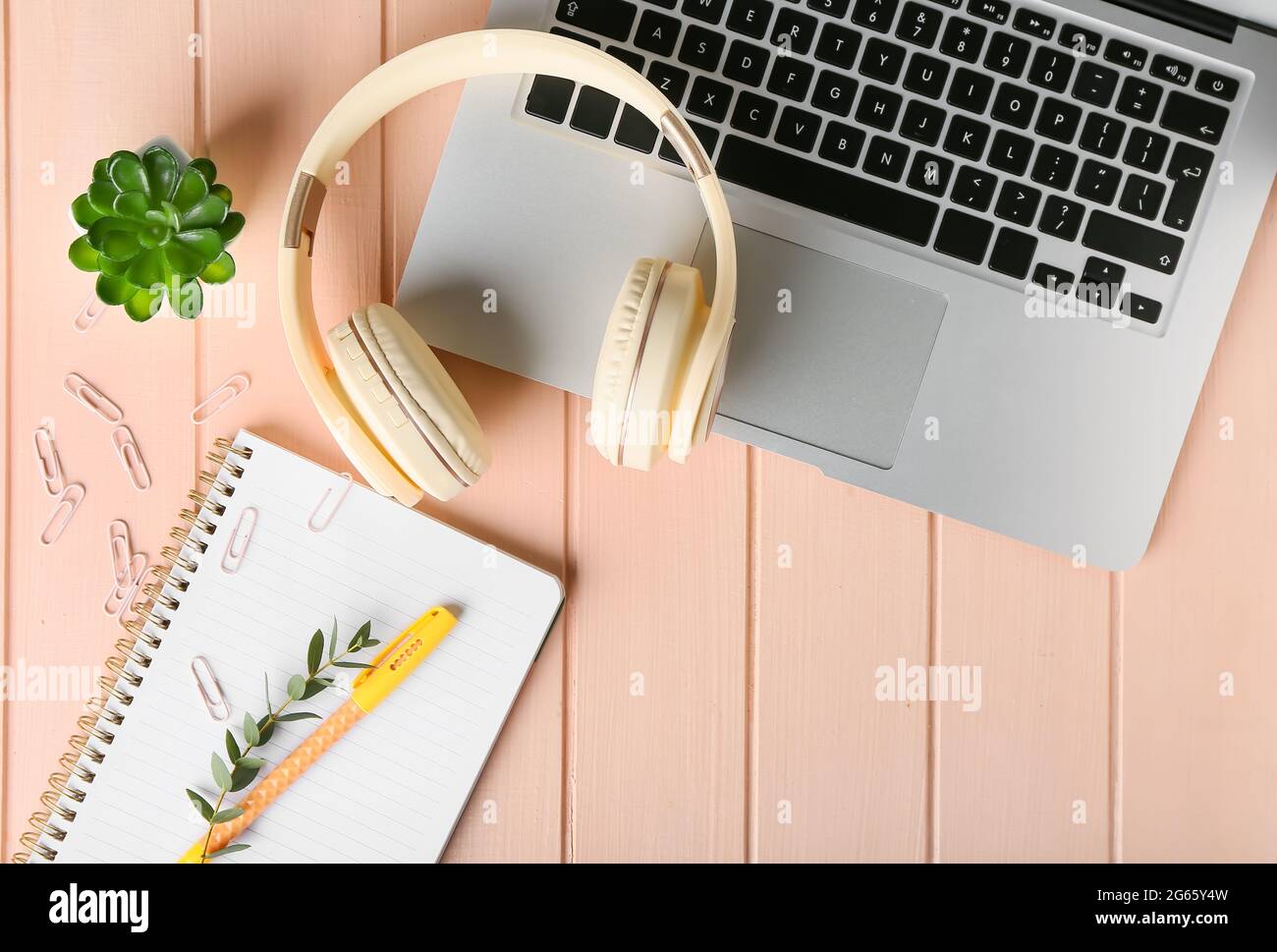 Cuffie moderne, computer portatile e notebook su sfondo in legno colorato Foto Stock