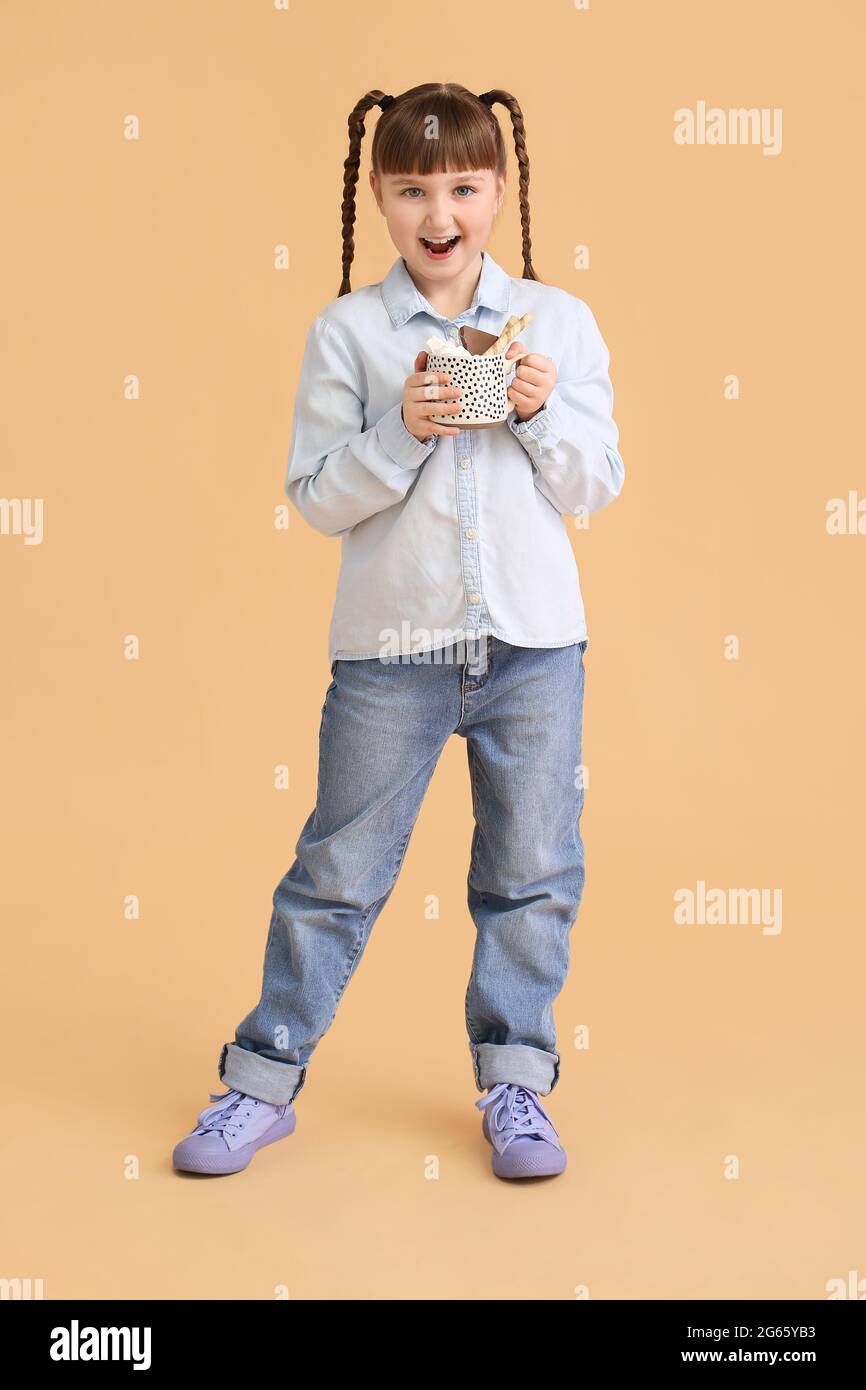 Bambina con tazza di cacao caldo su sfondo a colori Foto Stock