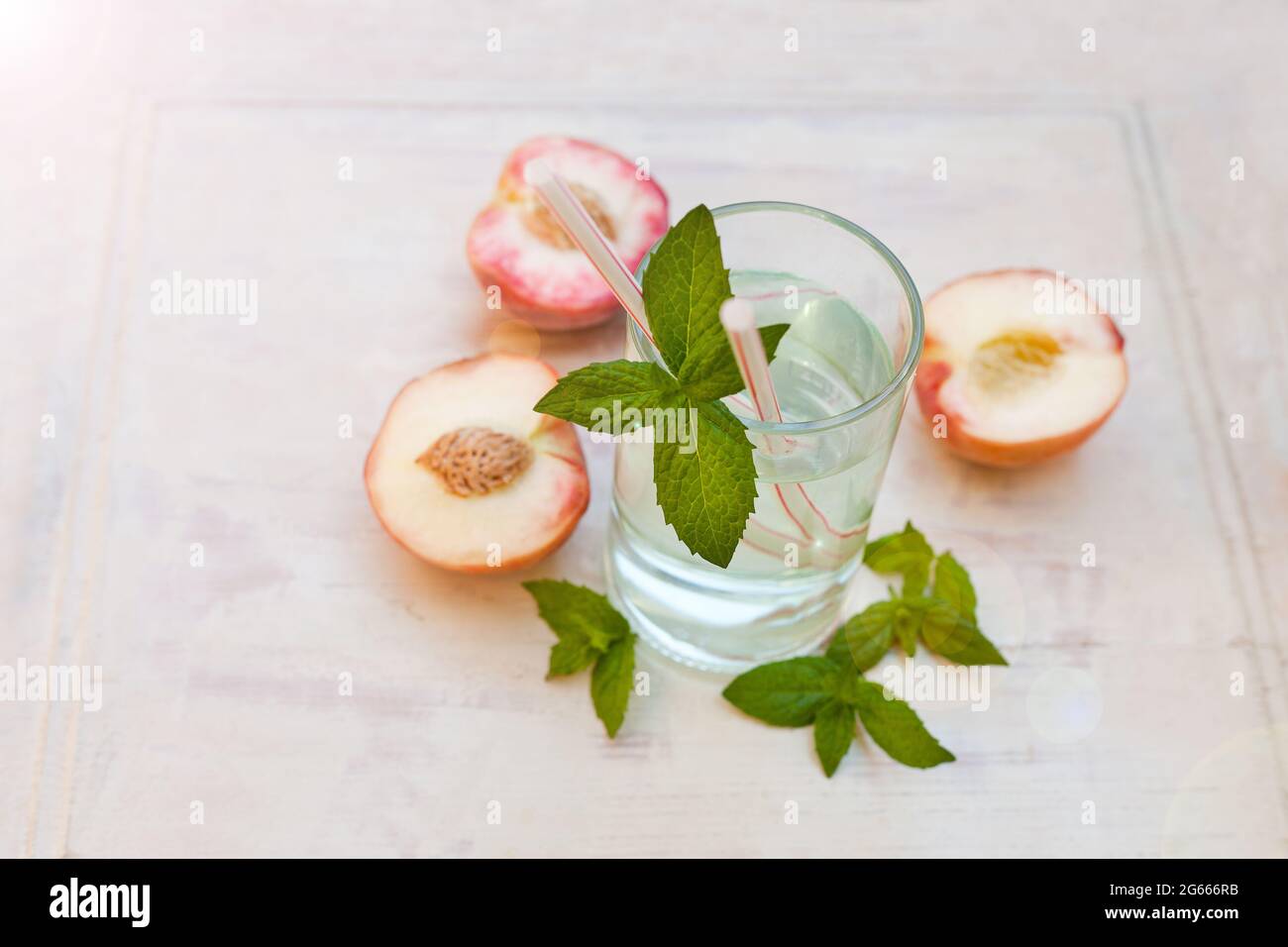 Rinfrescante tè freddo con menta piperita e pesche su sfondo grigio, fuoco selettivo. Bevanda ad acqua con pesche Foto Stock