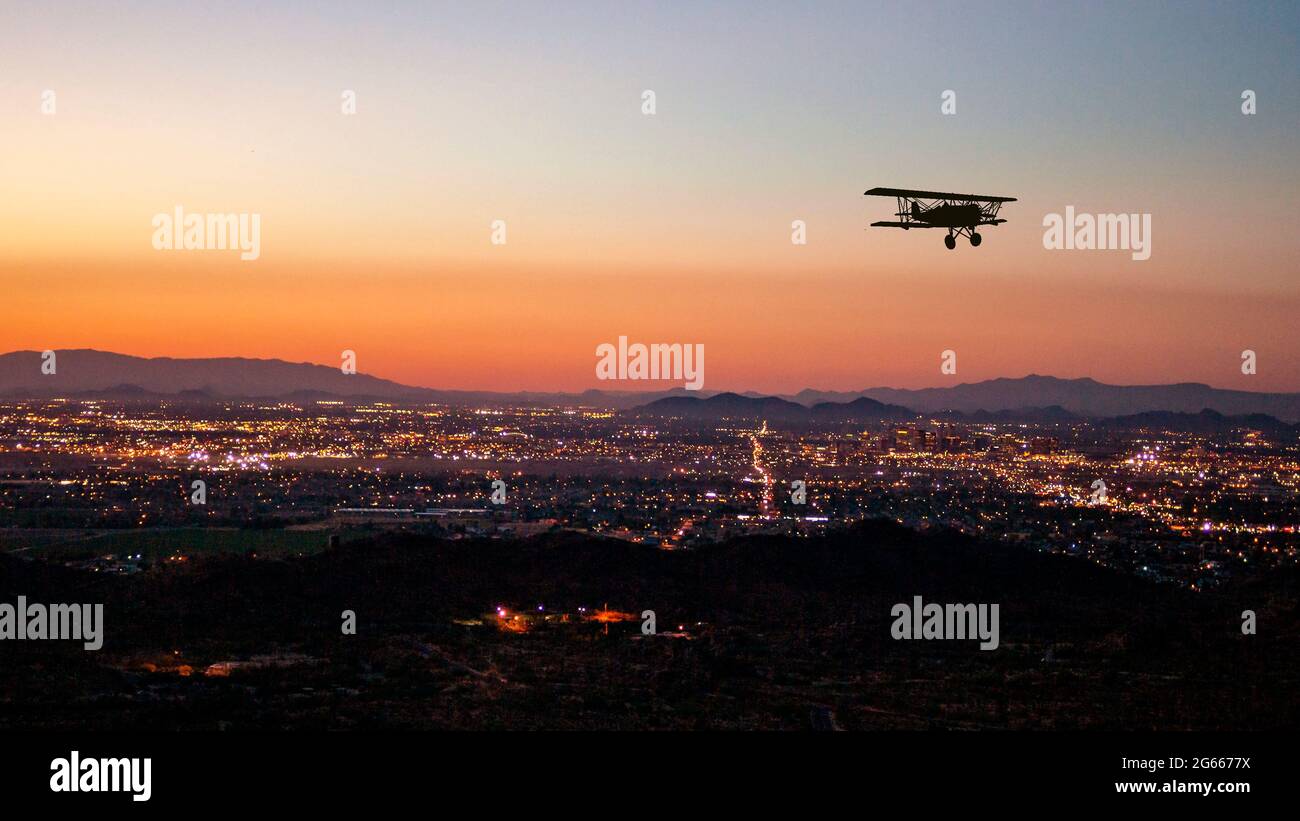 Composto da un biplano che sorvola Phoenix, Arizona, al tramonto Foto Stock