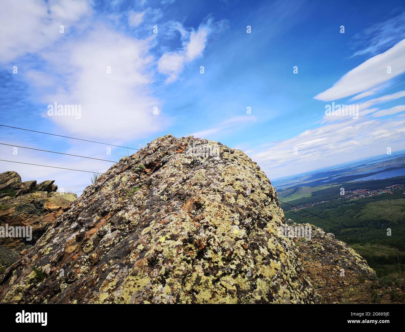 Una grande pietra sullo sfondo di montagne con alberi Foto Stock