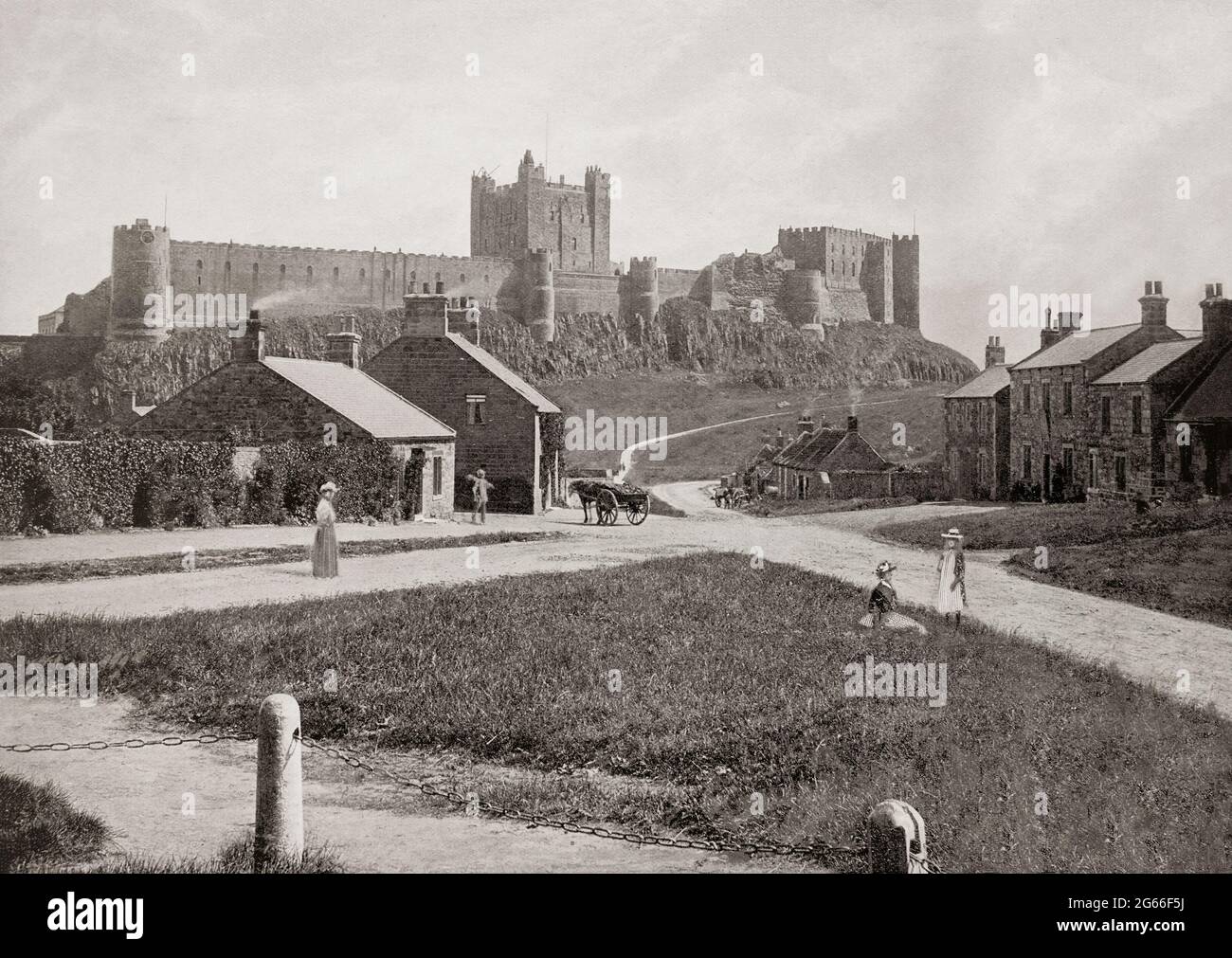 Una vista del tardo 19 ° secolo del villaggio sotto il Castello di Bamburgh in Northumberland, Inghilterra. I Normanni costruirono un nuovo castello sul sito, ed Enrico II probabilmente costruì il castello così come fu completato entro il 1164. Nel 1464, durante le Guerre delle Rose, divenne il primo castello in Inghilterra ad essere sconfitto dall'artiglieria, alla fine di un assedio di nove mesi da parte di Richard Neville, sedicesimo conte di Warwick, il 'Kingmaker', per conto degli Yorkisti. Nel 1894, il castello fu acquistato dall'industriale vittoriano William Armstrong, che completò il restauro. Foto Stock