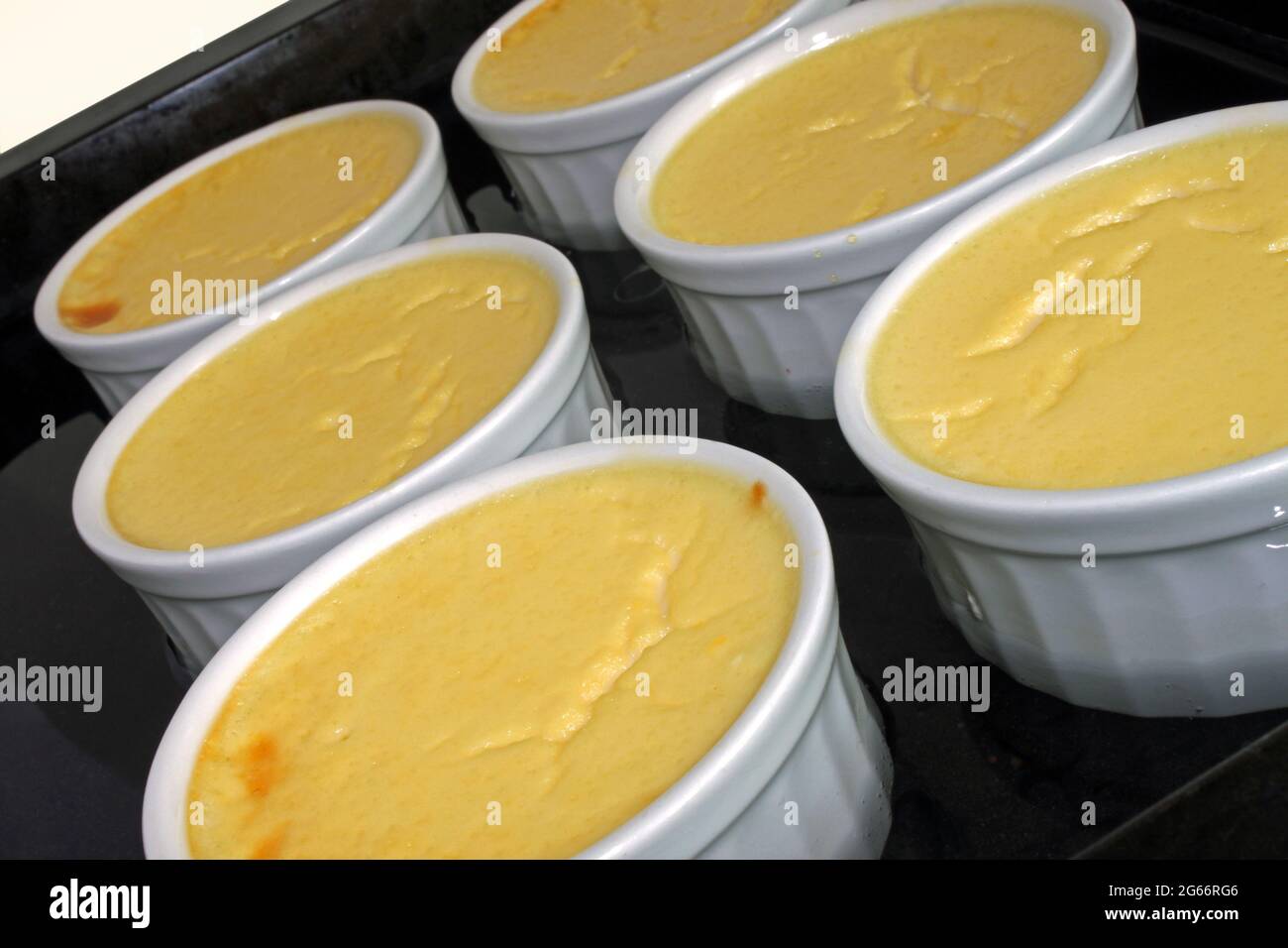 Sei crème caramello in una Bain Marie. Foto Stock