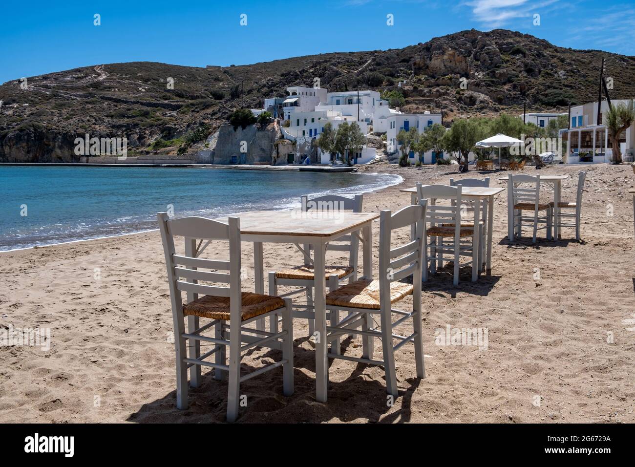 Taverna all'aperto dell'isola greca. Taverna tipica sul mare tavolo e sedie. Posti a sedere vuoti, giornata di sole al ristorante di pesce e frutti di mare del porto di Kimolos. vca. Estate Foto Stock