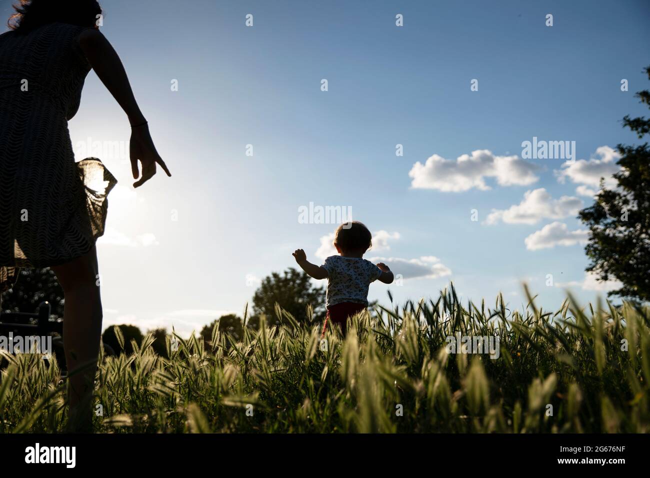 Un bimbo che si allontana dalla madre in un parco Foto Stock