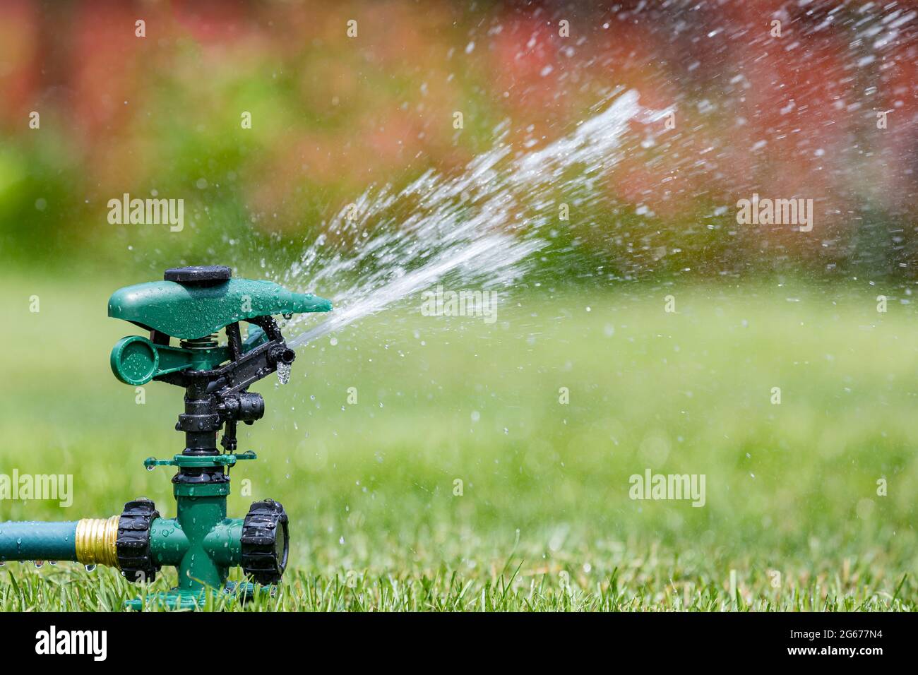Prato irrigatore erba in cortile. Uso dell'acqua, limitazioni e concetto di assistenza legale Foto Stock