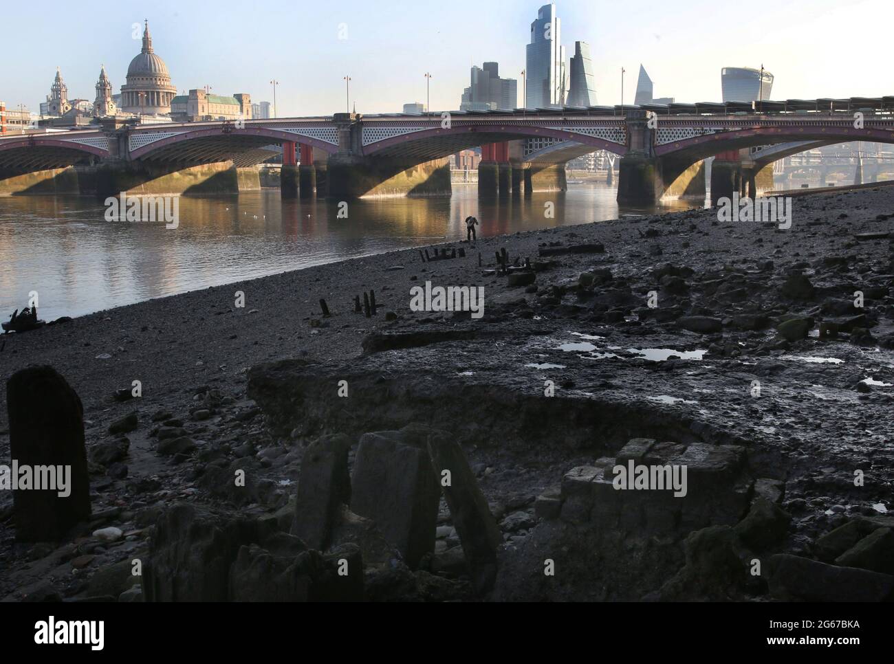 Alcune figure solitarie ricercano le rive del Tamigi per monete e trinket da un'epoca passata dominata dallo skyline della città a bassa marea.The rive del fiume gradualmente crescere come il Tamigi raggiunge la bassa marea. Le spiagge ben note ai fangatori e ai beachcomber e visibili solo per un paio d'ore al giorno danno londinesi, oltre un anno in blocco, in qualche luogo diverso da camminare ed esplorare. Foto Stock