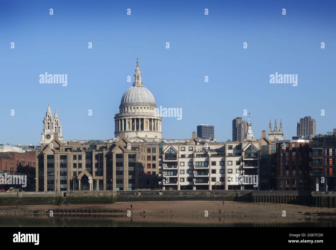 Londra, Regno Unito. 27 Feb 2021. Alcune figure solitarie cercano i trinket mentre una piccola spiaggia di sabbia appare all'ombra della Cattedrale di San Paolo sulle rive del Tamigi a bassa marea. Le rive del fiume crescono gradualmente quando il Tamigi raggiunge la bassa marea. Le spiagge ben note ai fangatori e ai beachcomber e visibili solo per un paio d'ore al giorno danno londinesi, oltre un anno in blocco, in qualche luogo diverso da camminare ed esplorare. Credit: Martin Pope/SOPA Images/ZUMA Wire/Alamy Live News Foto Stock