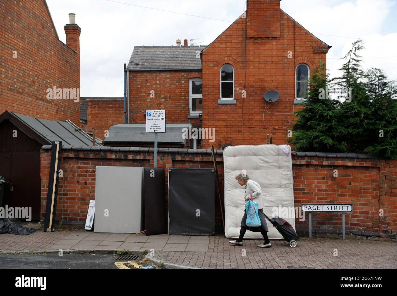 Loughborough, Leicestershire, Regno Unito. 3 luglio 2021. Una donna anziana passa accanto ai rifiuti lasciati per le strade dagli studenti universitari che lasciano le loro case Foto Stock