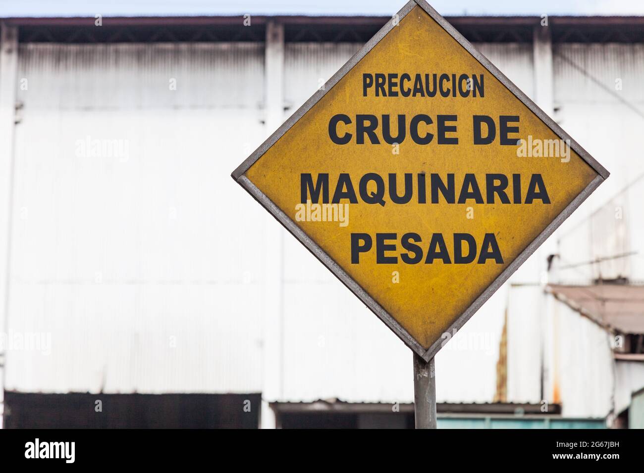 Cartello giallo con la scritta ´Precaucion Cruce de Maquinaria Pesada' (avvertimento incrocio di piante pesanti) in spagnolo Foto Stock