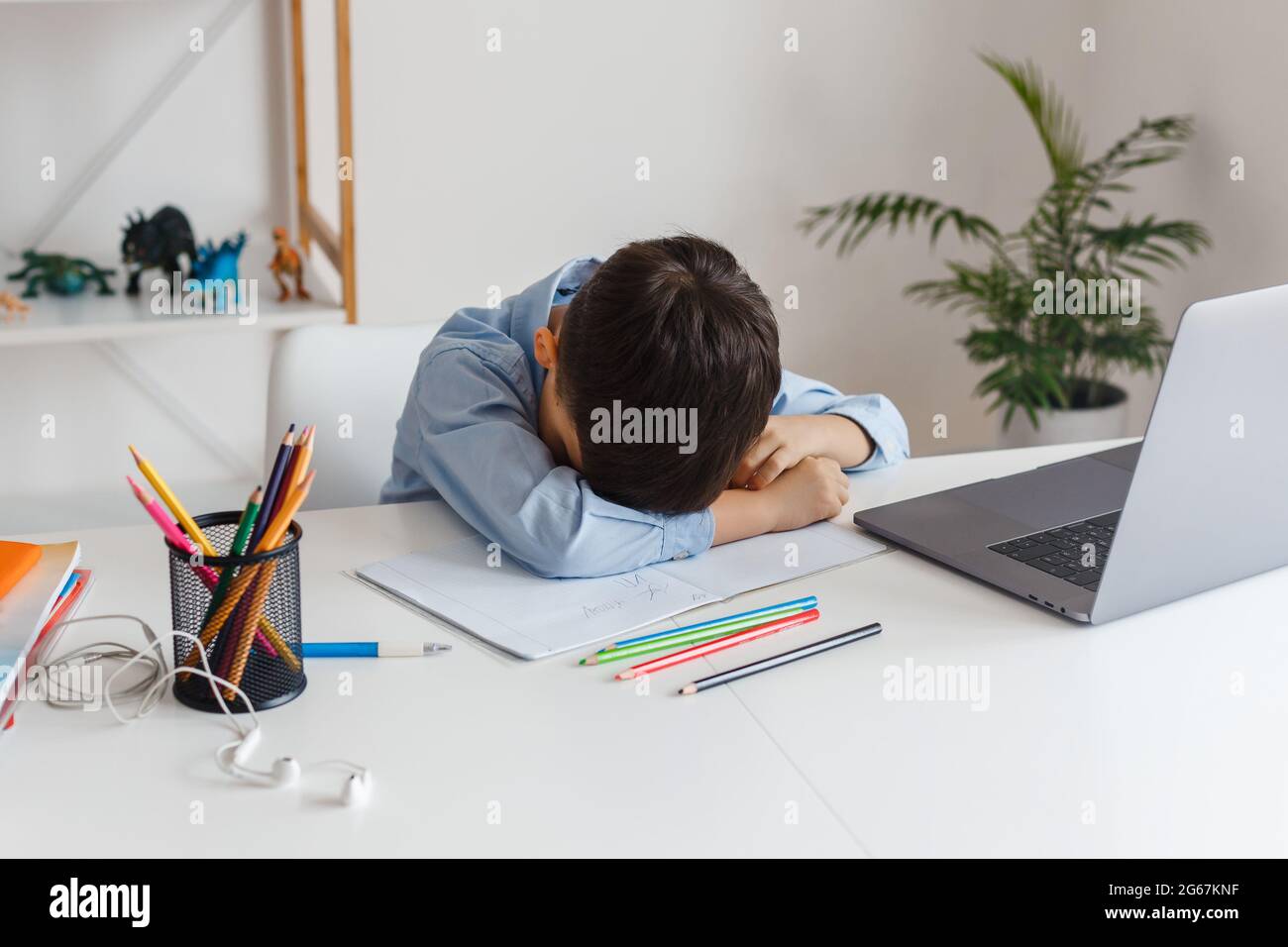 Bambino intelligente stanco di imparare compiti difficili utilizzando il computer portatile e Internet. E-learning scuola elementare tramite videochiamata. Ragazzo che studia online a casa Foto Stock