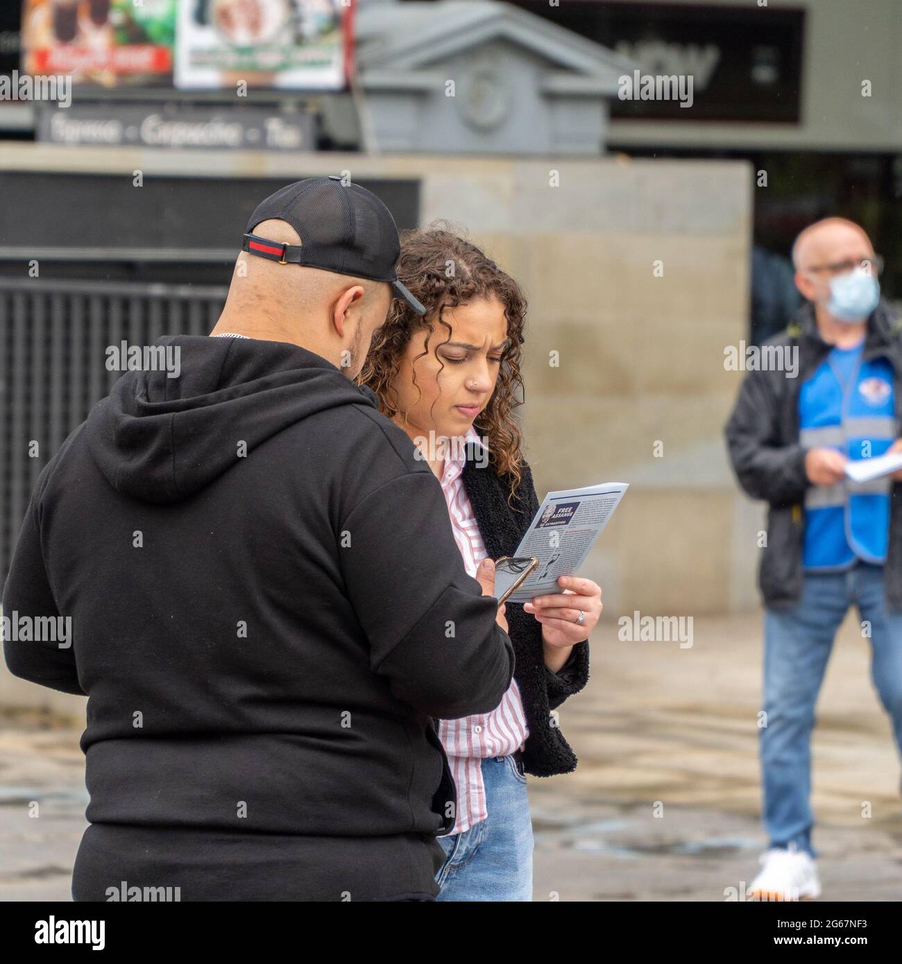 The Mound, Edinburgh, Scotland, UK, 3 luglio 2021: Due membri del pubblico, hanno letto un opuscolo Julian Assange. I sostenitori di Julian Assange scesero per le strade di Edimburgo per celebrare il 50° compleanno di Julian, una delle tante celebrazioni che si svolgono oggi in tutto il mondo. Julian Assange è ancora detenuto nella prigione di Belmarsh, mentre il governo degli Stati Uniti sta cercando di estradarlo in America, per le pubblicazioni di informazioni trapelate sul suo sito web wikileaks. Il 4 gennaio 2021, un tribunale britannico blocca l'estradizione. (Credit: Barry Nixon/Alamy Live News) Foto Stock