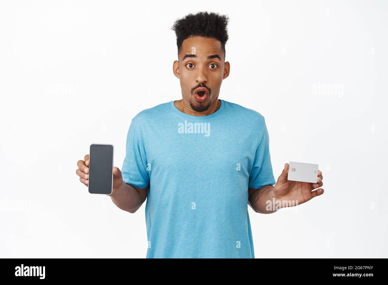 Ritratto di un ragazzo afro-americano eccitato che mostra lo schermo vuoto del telefono cellulare, carta di credito, stupito gastping, check out negozio di smartphone, negozio di internet Foto Stock