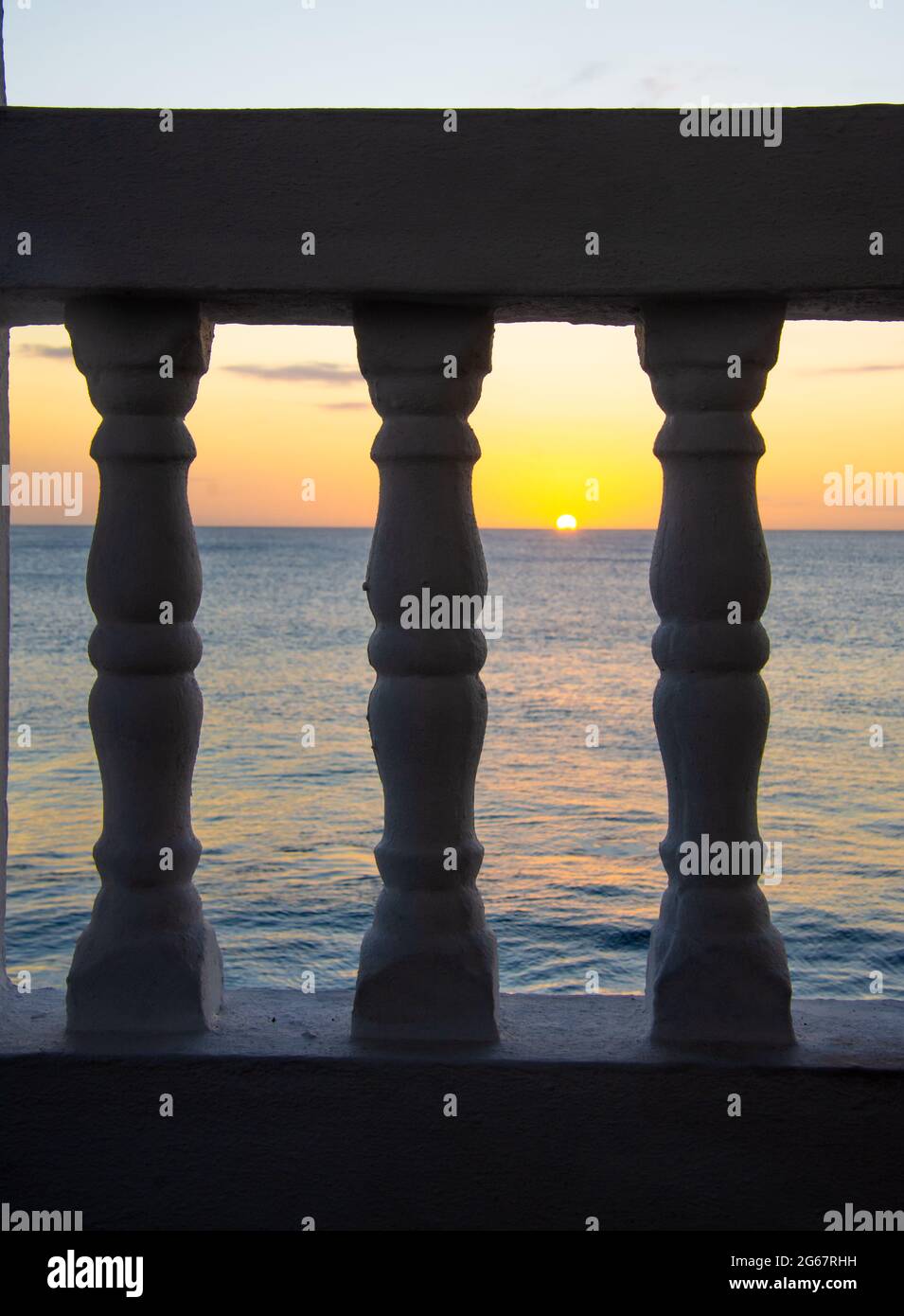 Vista del sole tramontante attraverso le balaustre su un balcone fronte spiaggia. Rincon, Porto Rico, Stati Uniti Foto Stock