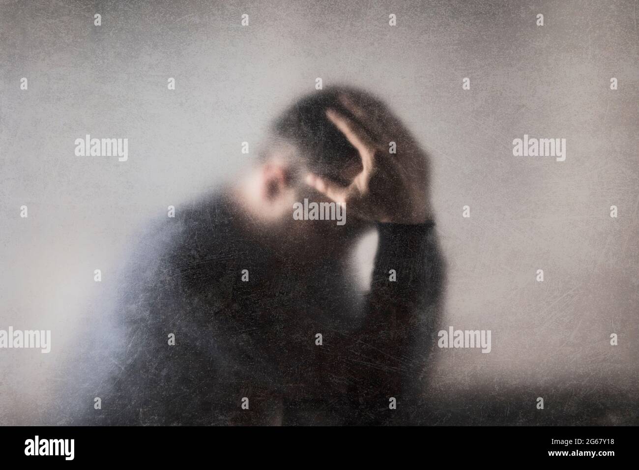 La depressione. Rotture di uomo dietro un polveroso vetro graffiato. Foto Stock