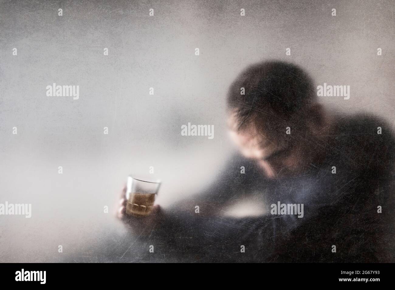 Uomo con un bicchiere di whisky dietro un vetro polveroso graffiato. Concetto di alcolismo. Foto Stock