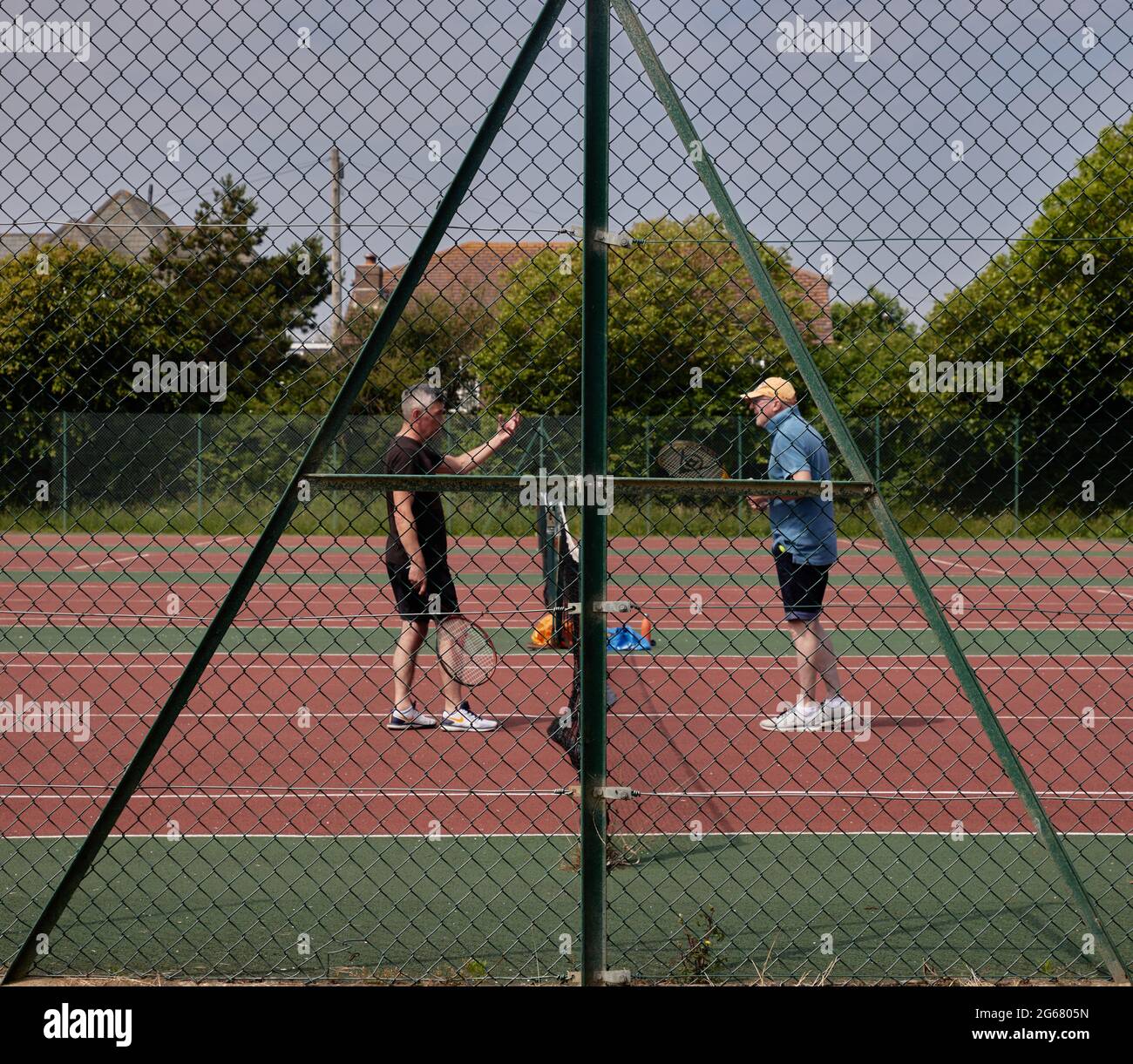 Due uomini che si preparano a giocare una partita di outdours di tennis nel regno unito durante l'estate del 2021. Foto Stock