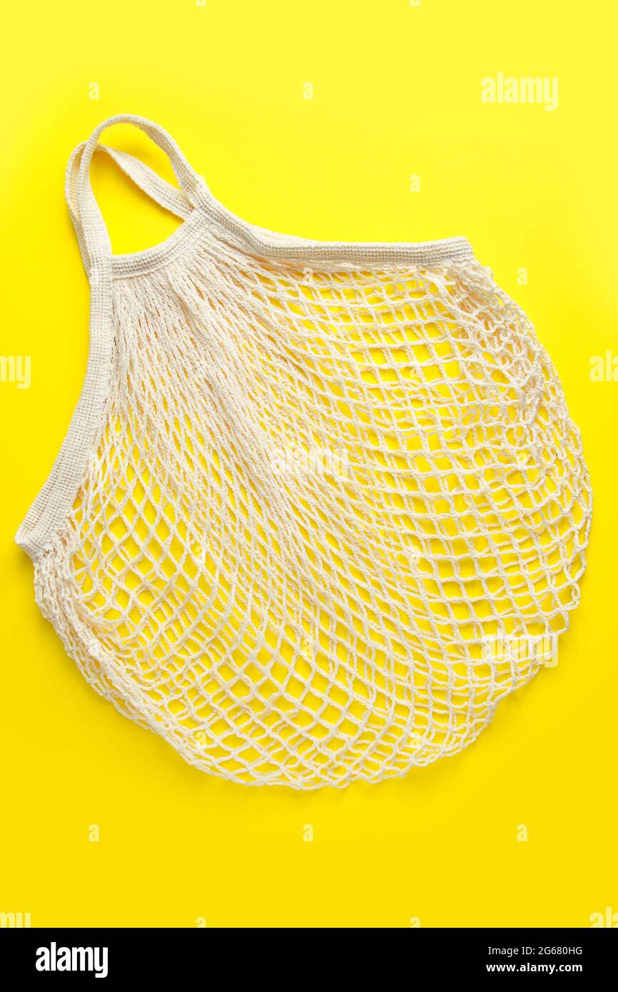 Borsa in mesh ecologica su sfondo giallo. Sacchetto di cotone biologico riciclabile. Stile di vita sostenibile e shopping. Foto Stock