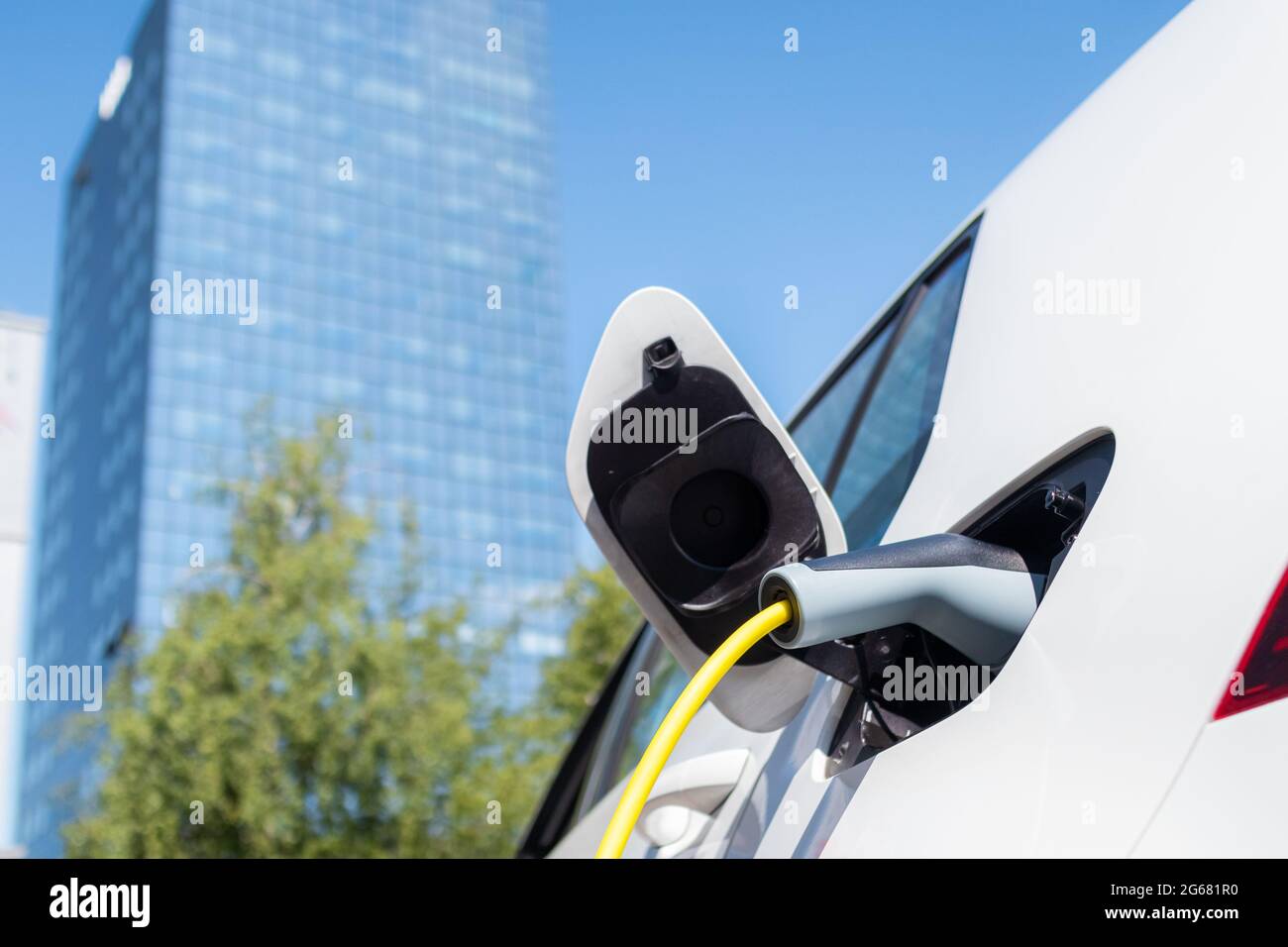Ricarica di un'auto elettrica in città con un cavo di alimentazione. Foto Stock