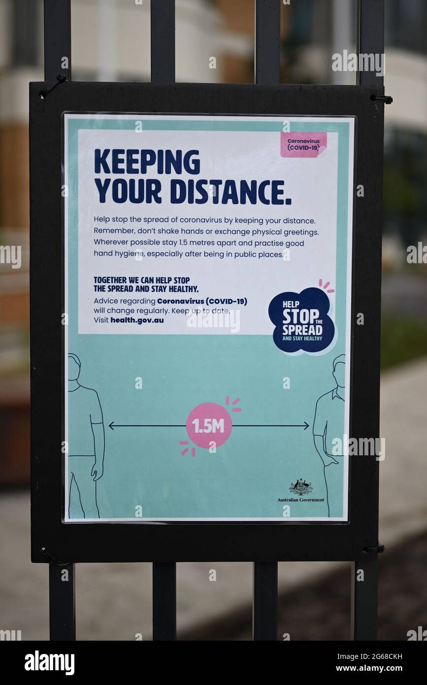Segno con i consigli di salute sul distanziamento sociale e l'igiene delle mani dal governo australiano su una recinzione, durante la pandemia COVID-19, dopo la pioggia Foto Stock