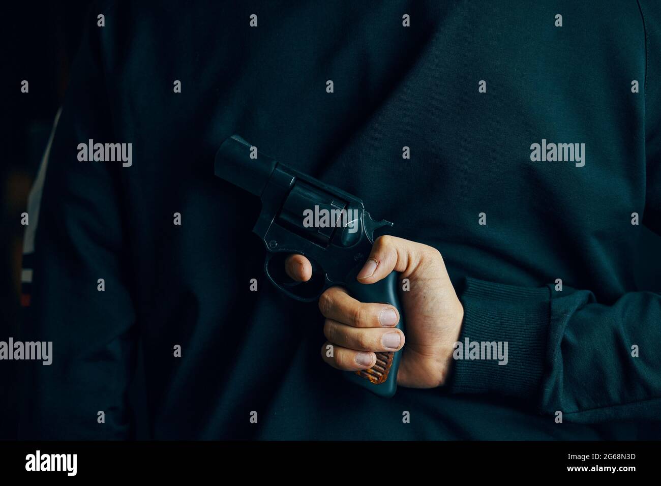 L'uomo tiene l'arma da fuoco dietro la schiena. Persona pronta ad attaccare con la pistola a mano. Revolver nella mano degli uomini. Foto Stock