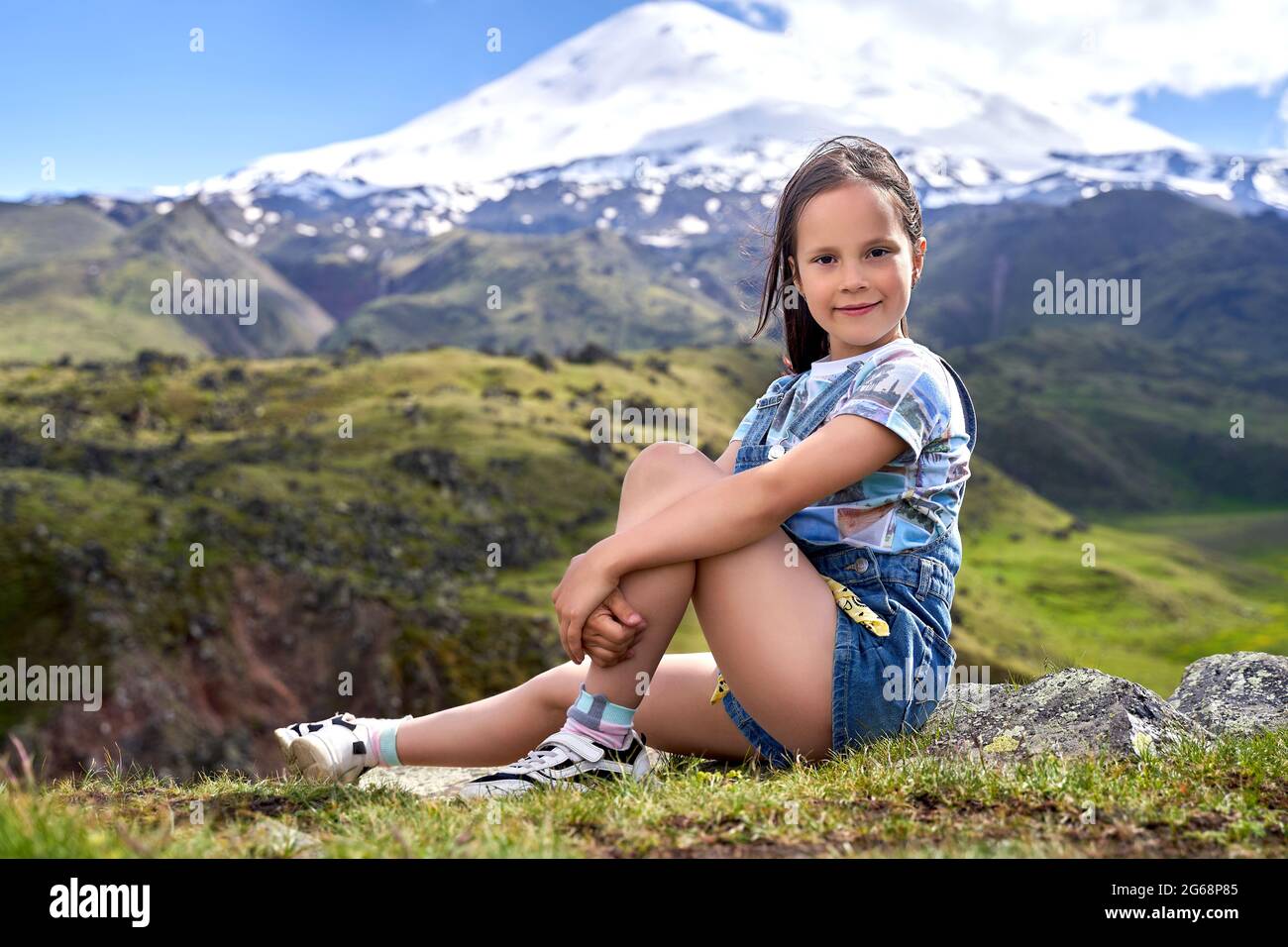 una bambina carina sullo sfondo delle cime di montagna. Foto Stock