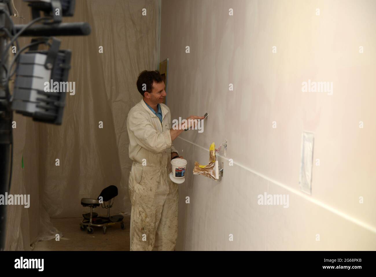 un tradesman riempie i fori per le unghie finali in un muro prima di dipingere Foto Stock