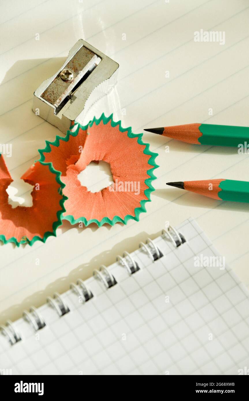 Matite di legno verde e blocco note aperte con affilatrice a matita su carta bianca foderata Foto Stock