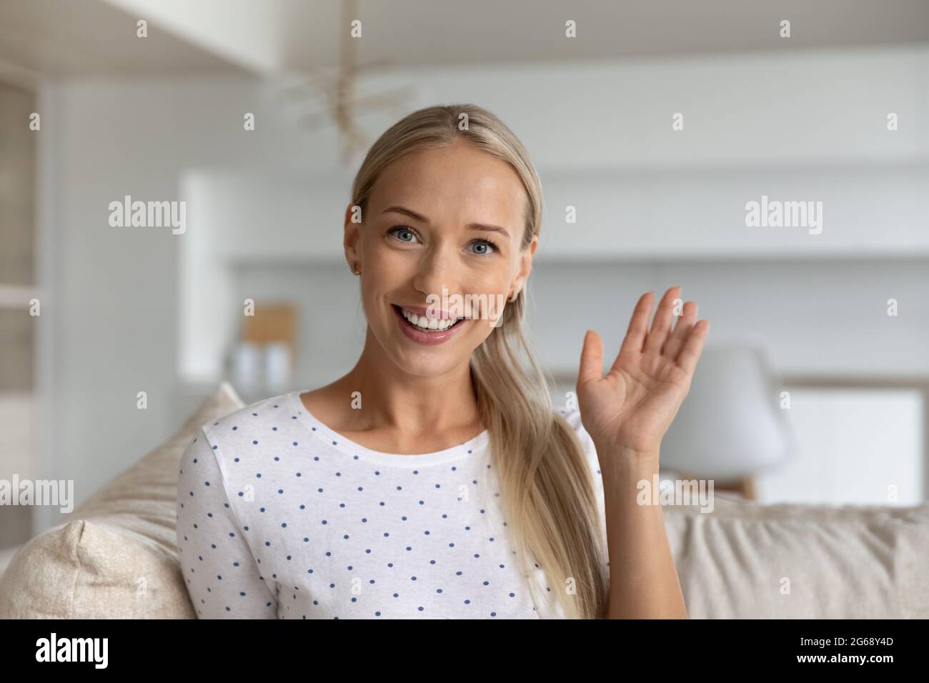 Testa ritratto di donna sorridente che agita la mano alla fotocamera Foto Stock