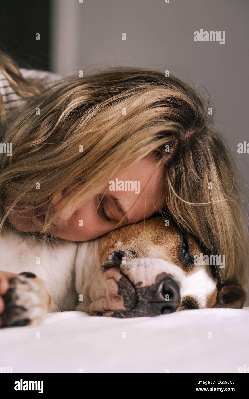 La giovane donna si trova vicino al suo cane e la abbraccia. Compagnia emozionale e stile di vita domestico con animali domestici Foto Stock