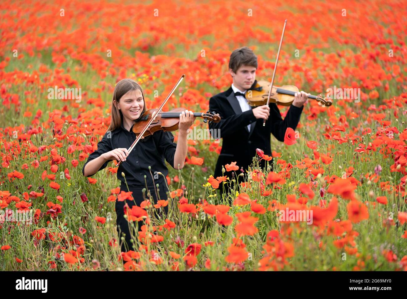 Viktor Seifert, 14 anni, e sua sorella Klara Seifert, 12 anni, suonano i violini Wilfred Owen e Siegfried Sassoon circondati da papaveri in un campo vicino a Edimburgo per celebrare cento anni del papavero come simbolo internazionale del ricordo. Data immagine: Domenica 4 luglio 2021. Foto Stock