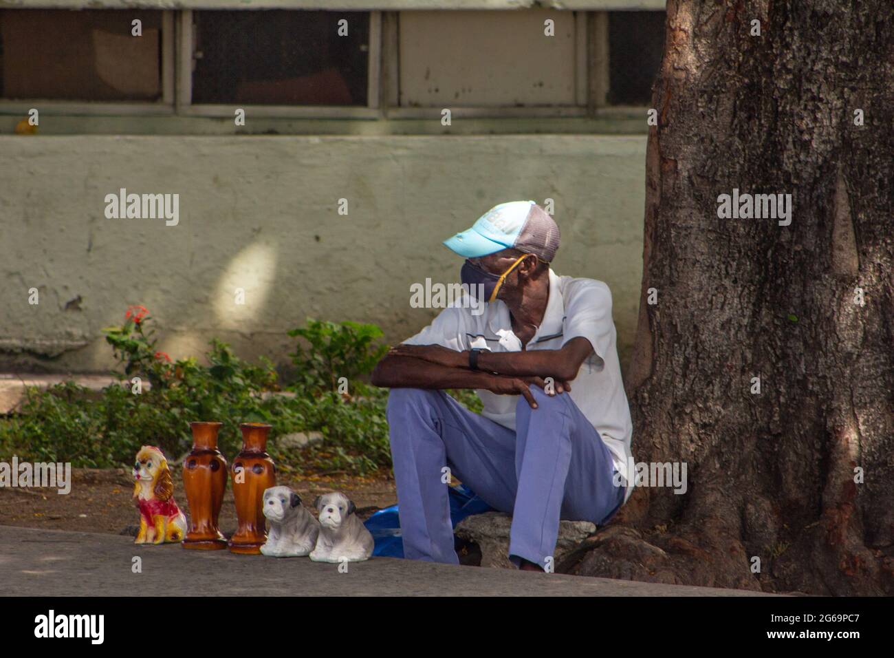 Un uomo cubano di etnia afro-caraibica vende elementi decorativi fatti in casa in un marciapiede della città a Santiago de Cuba, Cuba Foto Stock