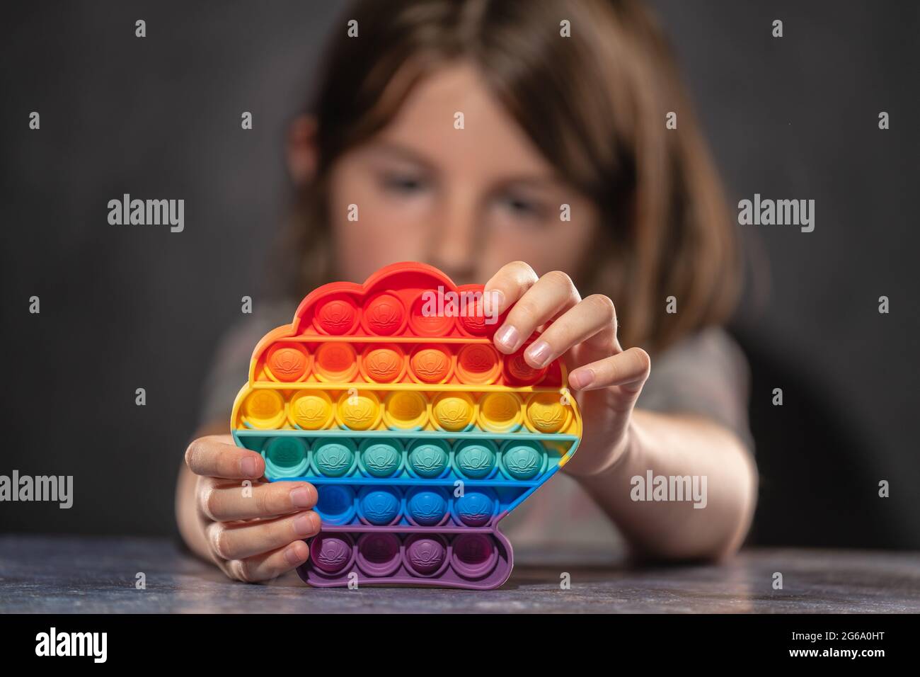 Bambina che gioca con arcobaleno colorato pop it silicone giocattolo antistress Foto Stock