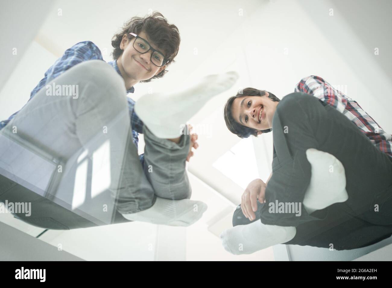 Basso angolo di padre e figli seduti su vetro Foto Stock