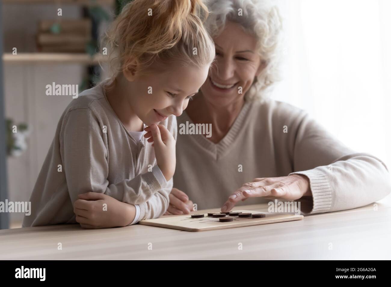 Anziana babysitter femminile impegnata nel gioco di logica con la ragazza preteen Foto Stock
