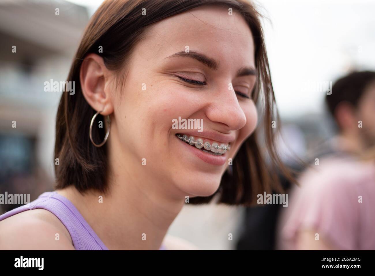 Giovane ragazza con pettinatura e t-shirt puкple sorridente con dentini metallici per la correzione del morso sui denti Foto Stock