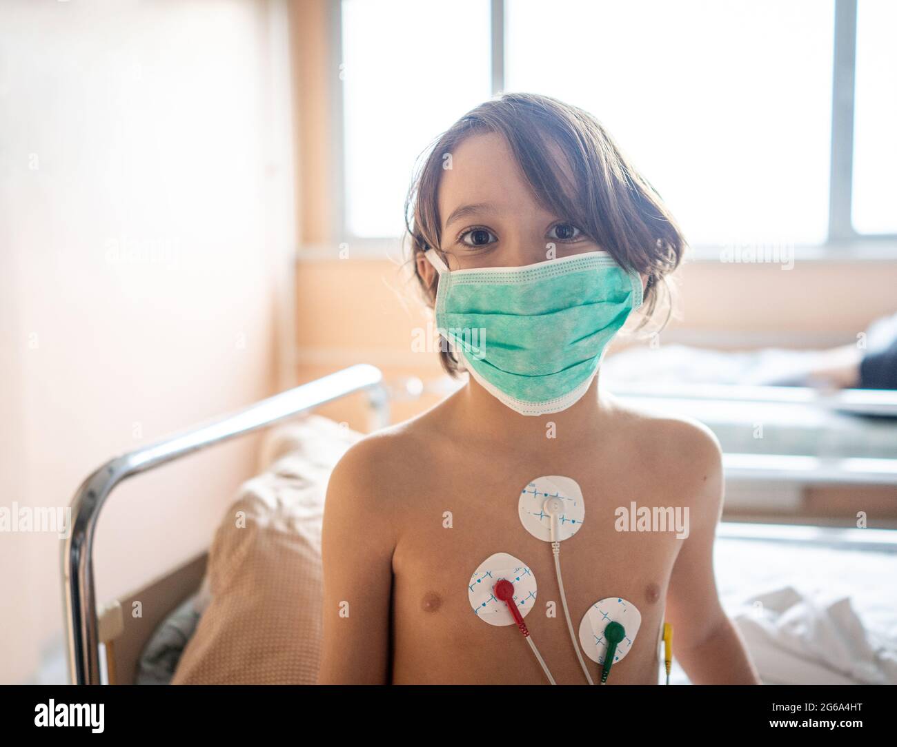 Piccolo ragazzo carino in ospedale a letto al coperto Foto Stock