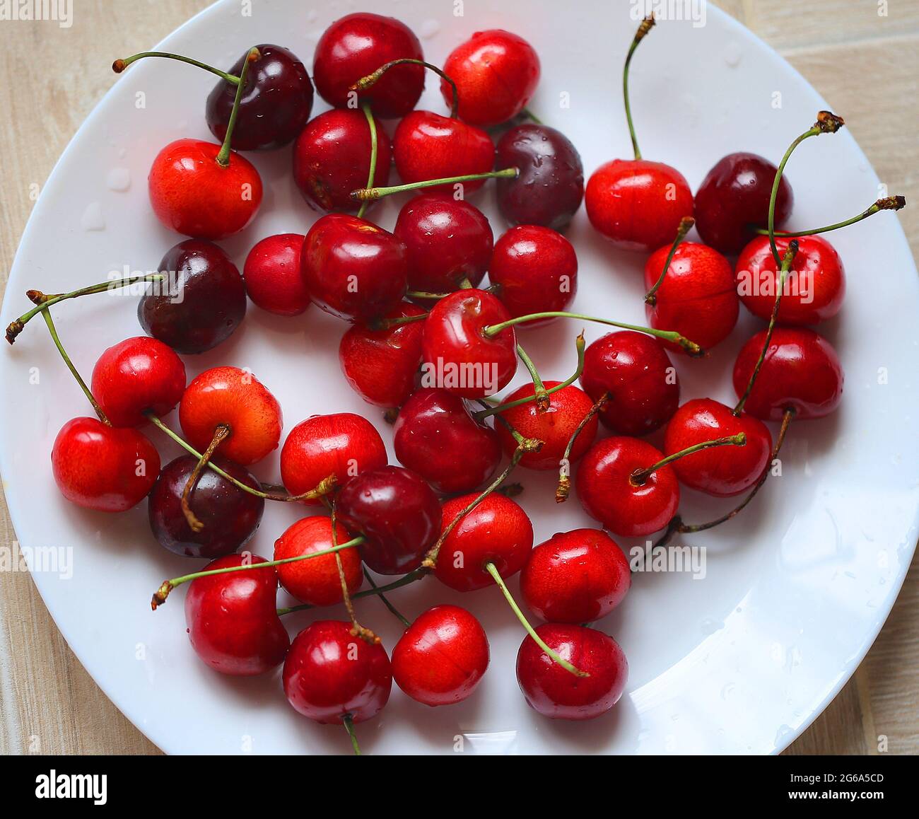 Macro ciliegie rosse mature su un piatto nella stagione estiva Foto Stock