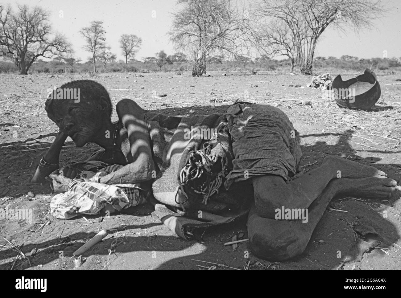 Botswana: Una vecchia donna dei boscimani che giace sulla sabbia all'ombra del Kalahari centrale pronta a morire presto Foto Stock