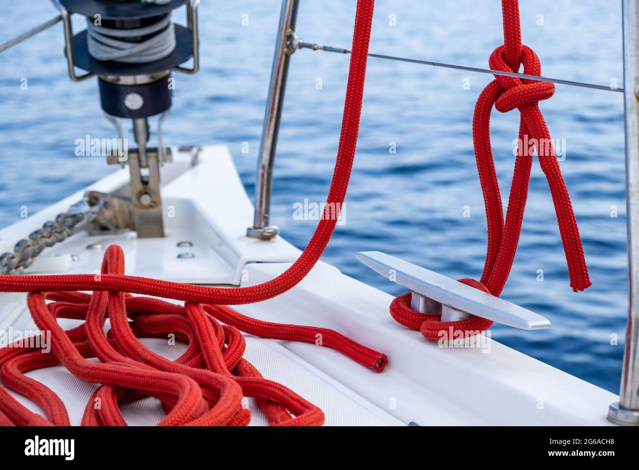 Barca a vela funi ormeggio sul ponte. Corda di yachting di colore rosso  legata su cleat, modello di scheda di crociera. Attrezzatura e strumenti di  sicurezza per la barca a vela, vista
