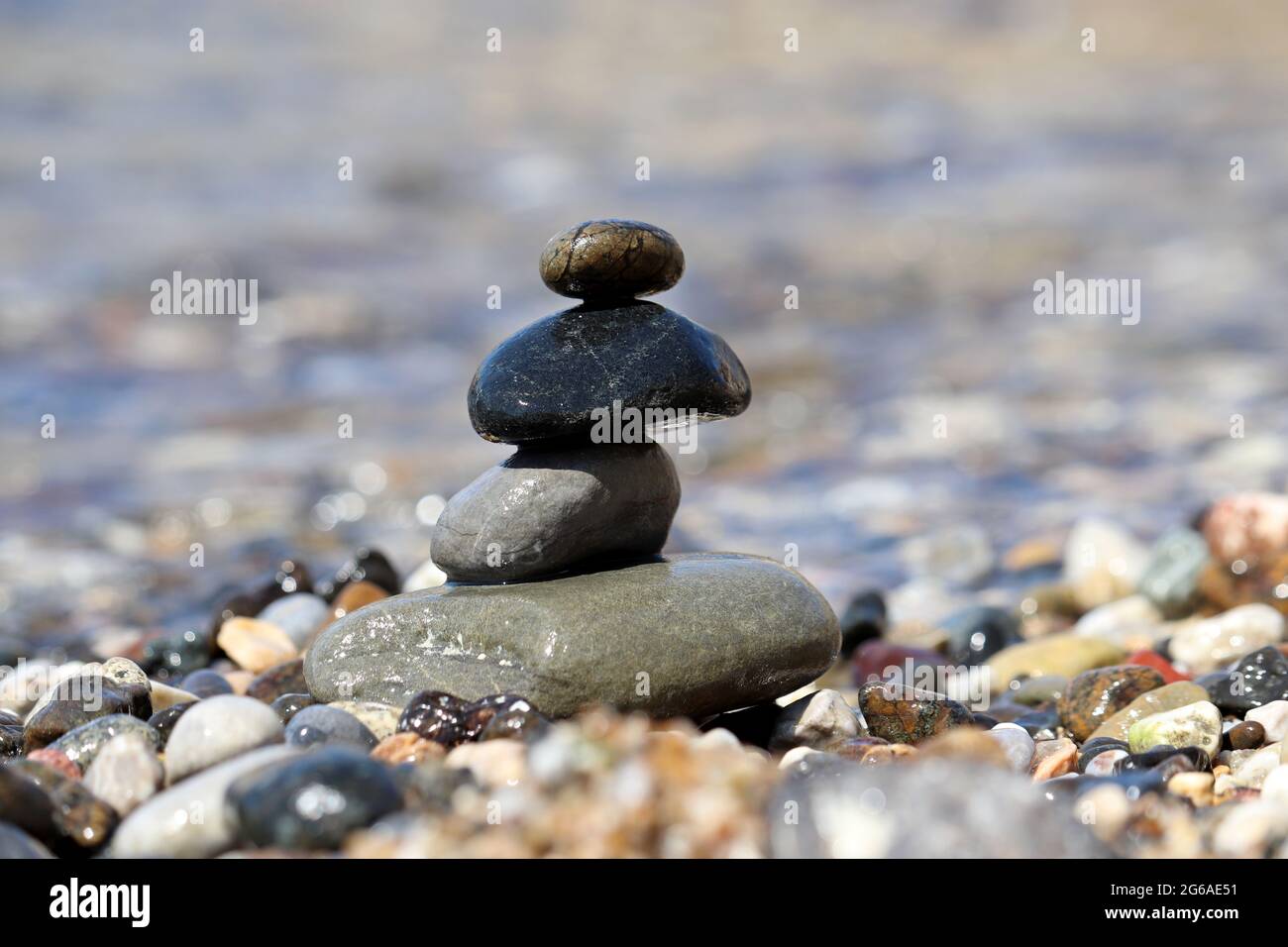Torre di ciottoli sullo sfondo delle onde del mare. Vacanza estiva, concetto di equilibrio e relax Foto Stock