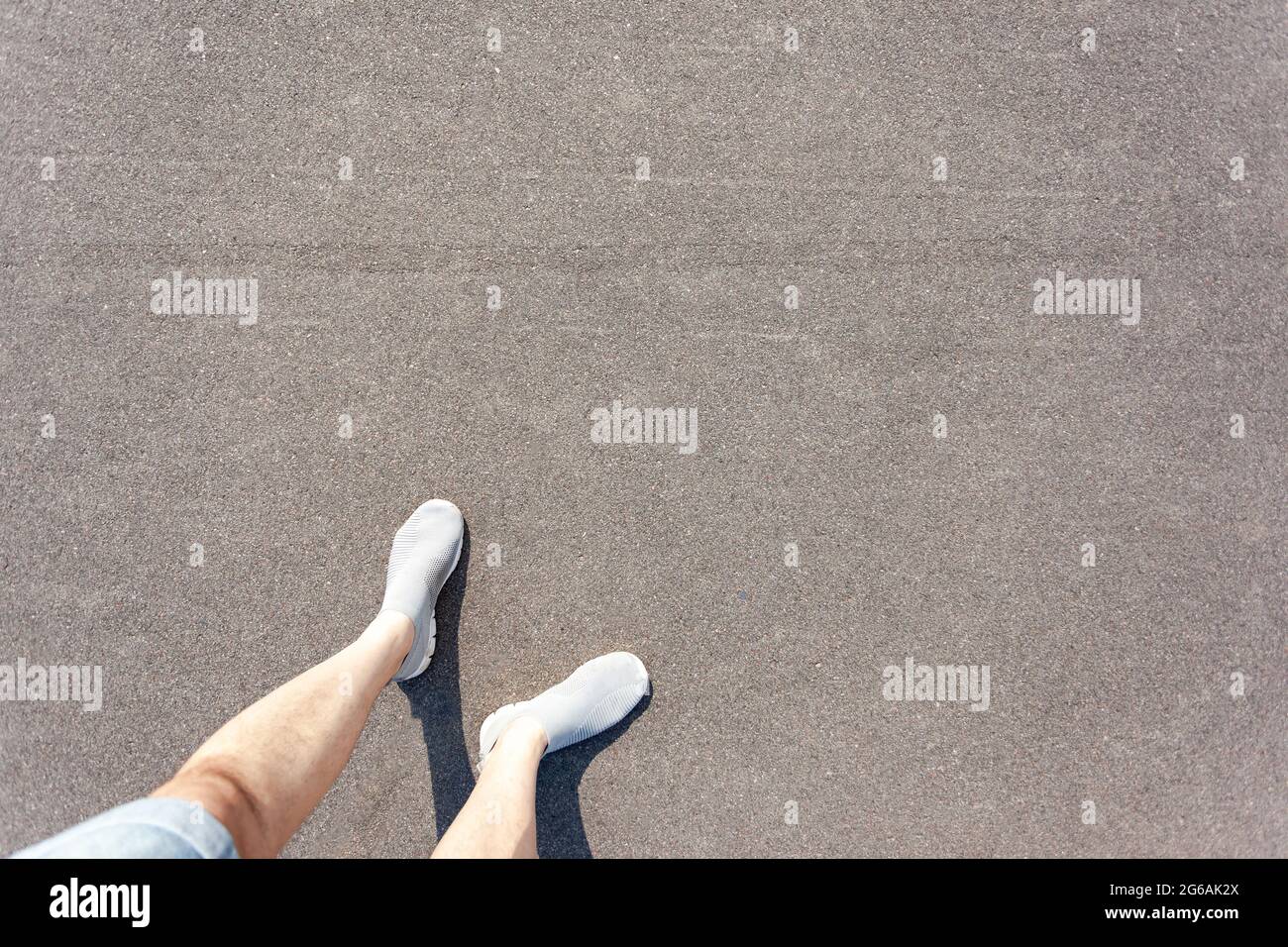 Piedi da uomo in pantaloncini e scarpe sull'asfalto, vista dall'alto Foto Stock
