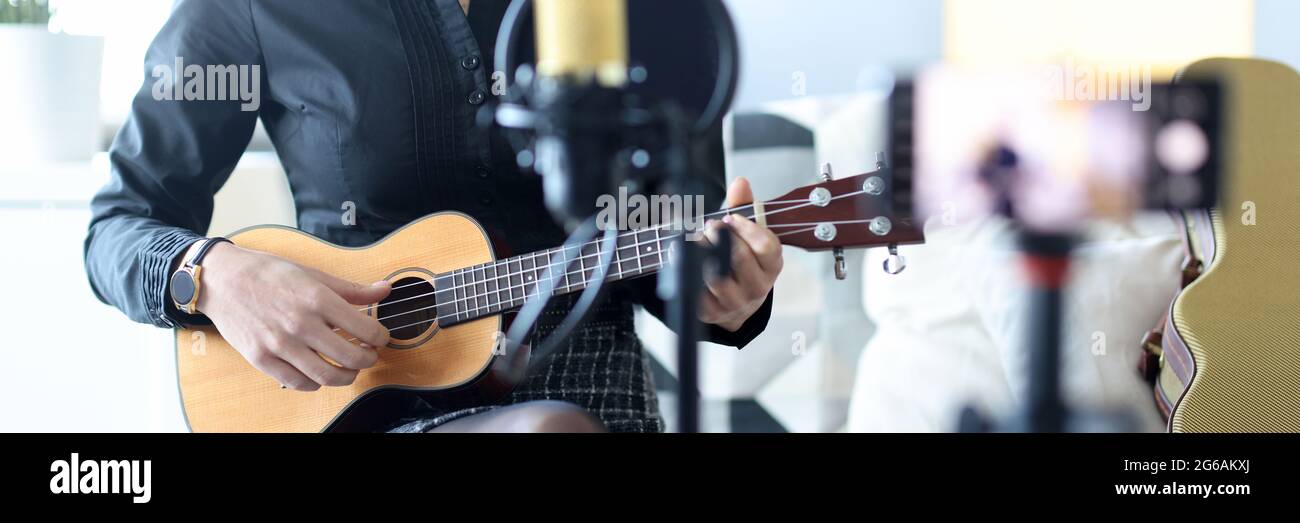 Donna gioca ukulele, e registra su smartphone Foto Stock
