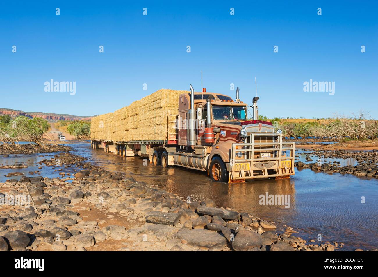 Treno stradale che trasporta fieno che attraversa l'iconica Pentecoste Crossing, Gibb River Road, il Kimberley, Australia Occidentale, WA, Australia Foto Stock